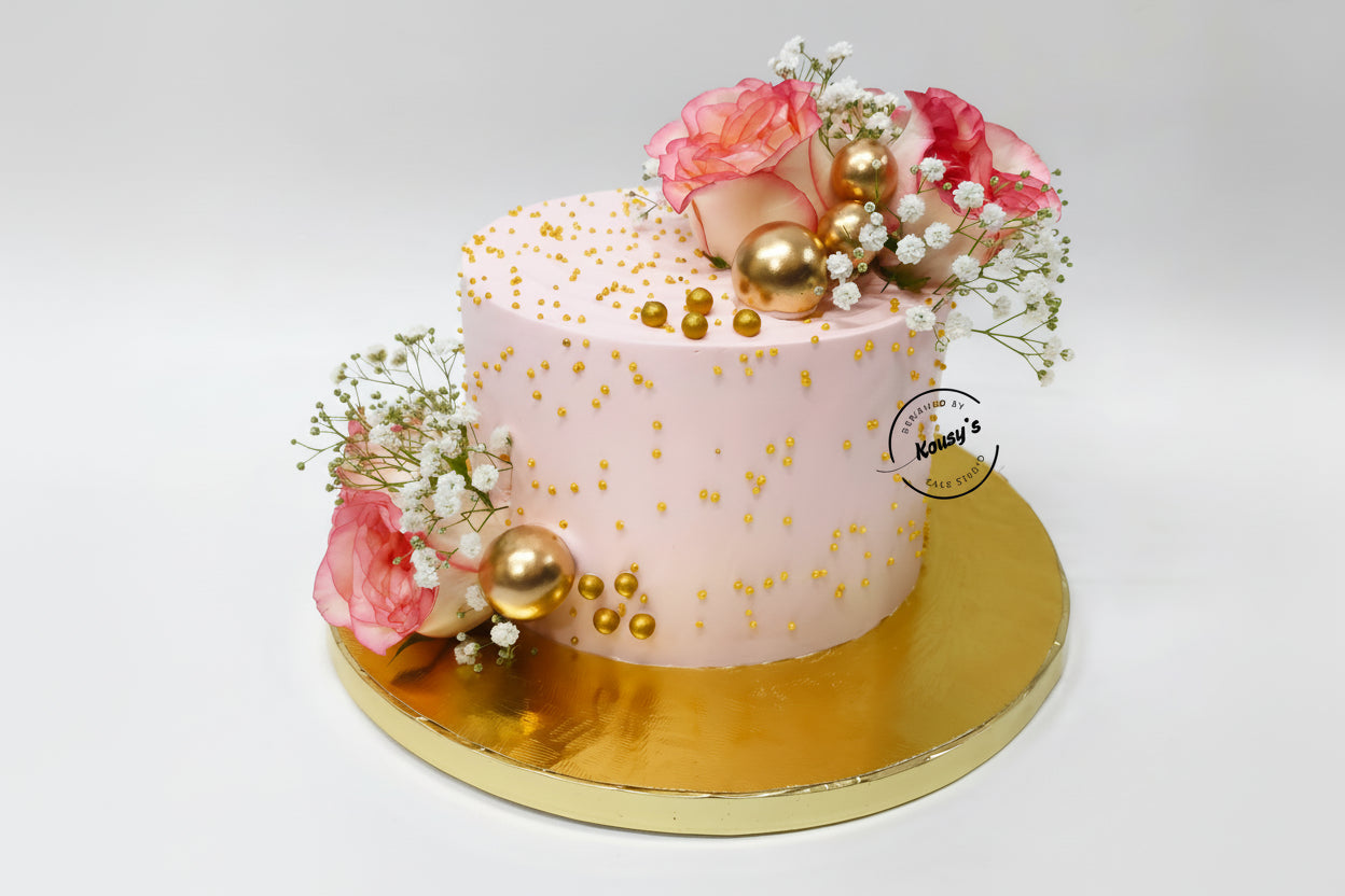 Pink cake with fresh flowers and gold balls on a white background