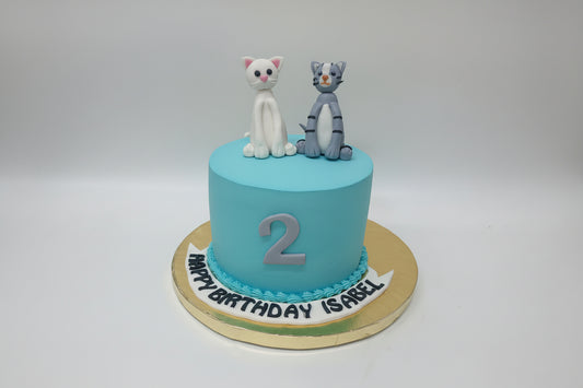Blue birthday cake with cat figurines  on a white background