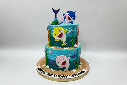 Two-tiered birthday cake with shark-themed decorations made by Kousy's cake studio
