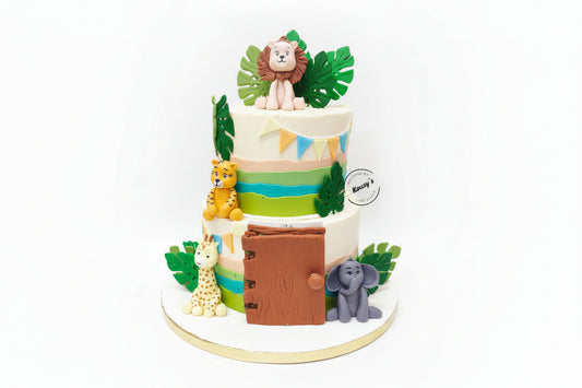 A Two-tiered Naming Ceremony cake with a jungle safari theme, decorated with animal figurines including a lion and elephant, and topped with a name reveal space.