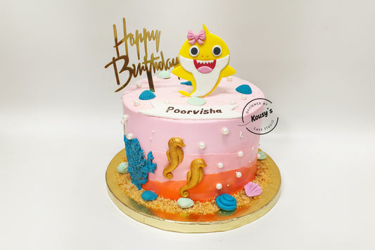 Birthday cake with a shark character and 'Happy Birthday' topper on a white background