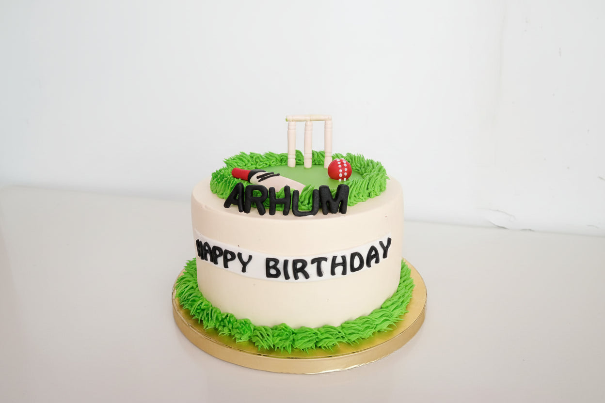 Birthday cake with cricket-themed decorations on a white background
