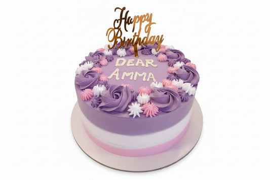 Birthday cake with purple frosting, pink and white flowers, and 'Happy Birthday Dear Amma' text on a white background.
