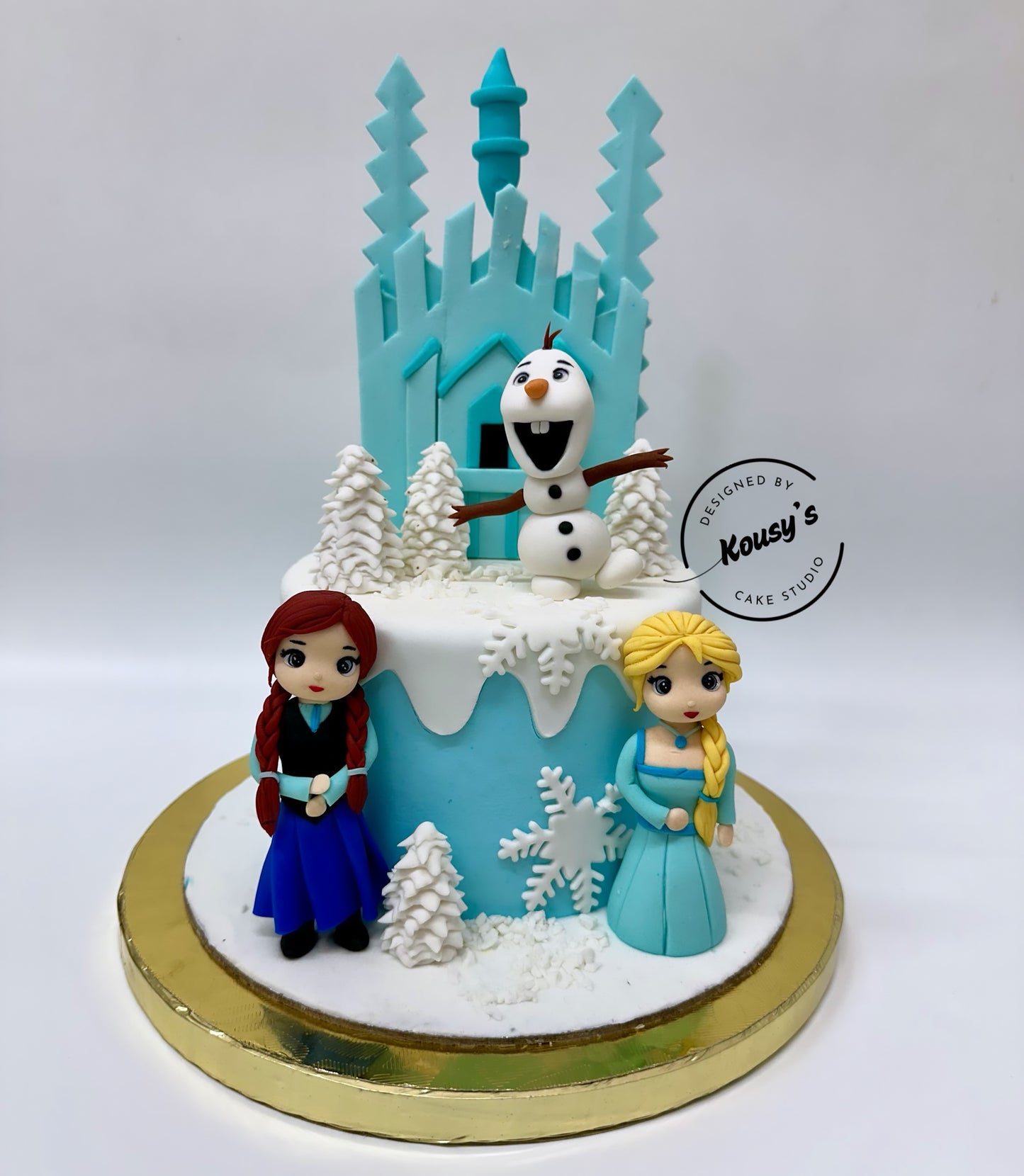 Frozen-themed cake with Elsa, Anna, and Olaf on a white background