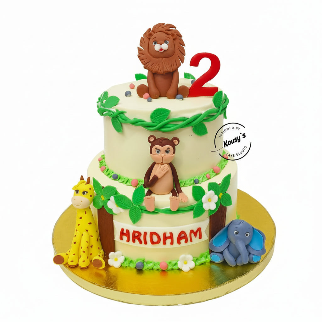 Two-tier birthday cake with animal figures and 'Hridham' on a white background