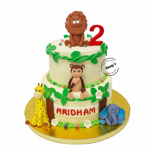 Two-tier birthday cake with animal figures and 'Hridham' on a white background