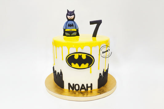 Batman-themed birthday cake with yellow icing, black bat symbol, and number 7 on a white background.
