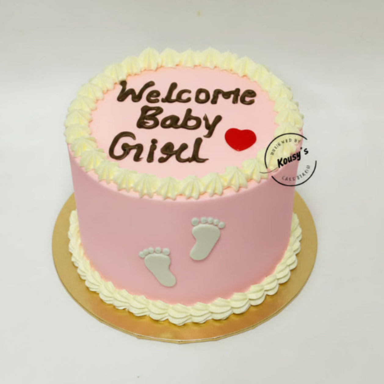 Pink baby shower cake with 'Welcome Baby Girl' text and footprints on a white background